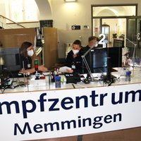 Der Empfangsbereich in der Alten Realschule ist abgebildet. Auf einem Transparent am Tresen steht in großen Lettern "Impfzentrum Memmingen"
