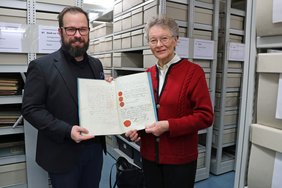 Der Oberbürgermeister und Gudrun Steinbauer halten die Urkunde in die Kamera.