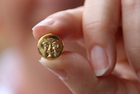 Der kleine Pin zeigt den Memminger Mau, ist kreisrund und golden. Etwas kleiner als der Fingernagel des kleinen Fingers. 