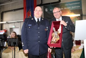 Der OB hält eine mit rotem Samt ausgekleidete Kiste in Händen, darin liegt eine barocke Figur des Heiligen in leuchtenden Farben mit Fahne.