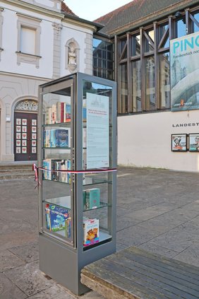 Der Bücherschrank mit seinen gläsernen Seiten und Türen..