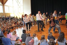 Auf der Tanzfläche in der Mitte tanzen Mütter und Väter, was Thomas Soukou vortanzt. In der 1. Reihe der Tänzer sind Oberbürgermeister Manfred Schilder und Bürgermeisterin Margareta Böckh.