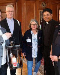 Oberbürgermeister Jan Rothenbacher nimmt von Roberto Kalz das Friedenslicht in einer Laterne entgegen. Dahinter die drei weiteren Personen. 