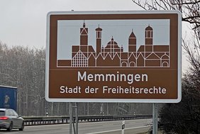 Autobahnschild "Memmingen Stadt der Freiheitsrechte" mit Autobahn im Hintergrund