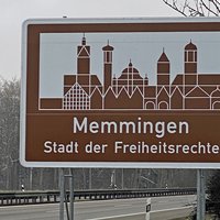 Autobahnschild "Memmingen Stadt der Freiheitsrechte" mit Autobahn im Hintergrund