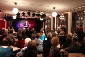 OB Schilder spricht zu den Frauen und Männern, die im Foyer des Landestheaters sitzen oder stehen.