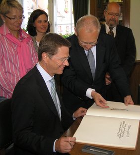 Oberbürgermeister präsentiert Guido Westerwelle das Goldene Buch der Stadt.