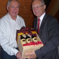 OB Dr. Holzinger übereicht einen Karton mit mehreren Flaschen Rotwein an Bernd Feil