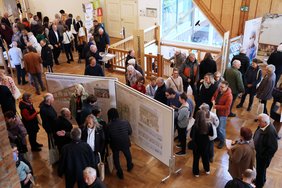 Blick von oben auf viele Menschen, die an Ständen oder Messetafeln stehen, im Gespräch miteinander sind oder zum nächsten Stand weitergehen