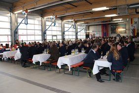 Blick auf die Fahrzeughalle mit den Toren für die Ausfahrten für Feuerwehrfahrzeuge. In der Halle ist eine Bühne für die Musik und die Redner aufgebaut, außerdem 36 Bierbankgarnituren für die Gäste.