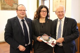 Oberbürgermeister Dr. Ivo Holzinger überreicht Dr. Verena Di Pasquale ein Buchgeschenk. Mit auf dem Bild: Ludwin Debong