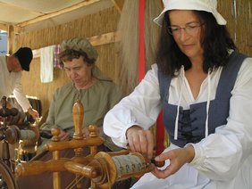Am historischen Spinnrad spinnen zwei Frauen.