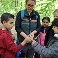 Die Kinder scharen sich um die Revierleiterin, die das kleine Geweih in Händen hält, die Kinder dürfen es befühlen.