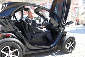 Der Bürgermeister sitzt in einem kleinen E-Auto.