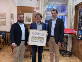 Dr. Singer steht in der Mitte und hält den Wächter Stich, Oberbürgermeister Jan Rothenbacher steht links, Referatsleiter Thomas Schuhmaier rchts.
