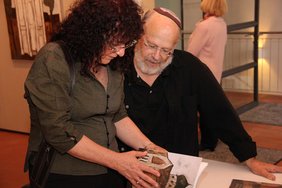 Frau Geva und Herr Bermann schauen in den Ausstellungskatalog