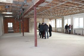 Ein großer Raum mit hellen Fenstern ist zu sehen, in dem die Gruppe steht.