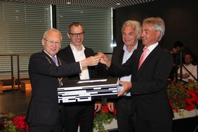 Zu sehen sind die vier Männer, die ein Modell der Schule in Händen halten.