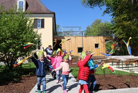 Die Kinder ziehen Fähnchen schwingend in den Garten ein.