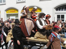 Auf ihrem Gauklerwagen ziehen die Spielleute durch die Stadt.