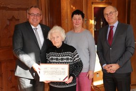 Das Bild zeigt die vier Personen im Amtszimmer. Frau Funke hält den Wechter-Stich in der Hand