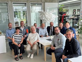 Die Personen sitzen auf Kinderstühlchen an den Tischen der Kinder.