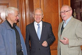 Die drei Herren stehen im Amtszimmer nebeneinander und unterhalten sich