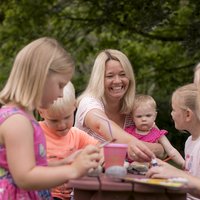 Frauen und Kinder sitzen im Freien an einer Bank.