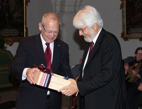 Dr. Holzinger überreicht ein Weinpräsent an Prof. Dr. Kießling