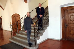 Die beiden Herren stehen am Geländer der Rathaustreppe im aktuell notwendigen Abstand von mindestens 1,5 Metern.