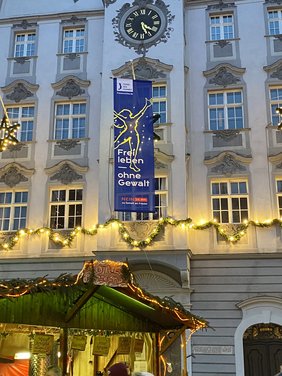 Blaue Fahne mit gelbem Symbol einer Frau und Text: "Frei Leben ohne Gewalt" Terre des Femmes