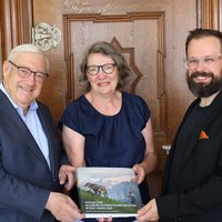 Gruppenfoto der drei Personen, alle drei halten gemeinsam ein Buchexemplar. 