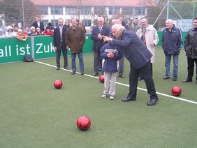 Bulle Roth und ein Kind vor dem Schuss aufs Tor. Im Hintergrund die Ehrengäste.