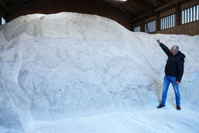 Herr Geikl steht vor einem großen Berg Salz, der deutlich höher ist als die Person.