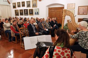 Beide Musikerinnen mit Instrumenten von hinten abgebildet. Über sie hinwegblickend ist das zahlreiche Publikum von vorne zu sehen.