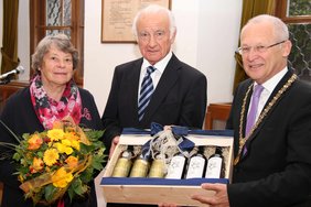 OB Dr. Holzinger überreicht ein Weinpräsent an Herrn Bilgram und Ehefrau Helga bekommt Blumen