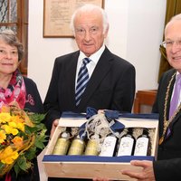 OB Dr. Holzinger überreicht ein Weinpräsent an Herrn Bilgram und Ehefrau Helga bekommt Blumen