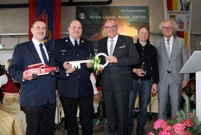 Die Herren stehen auf der Bühne halten einen großen bedruckten Schlüssel Symbol-Schlüssel in Händen.