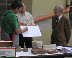 Grabungsleiter Fabian Hopfenzitz (links) stellt Oberbürgermeister Dr. Ivo Holzinger (rechts) einen Plan des ehemaligen Fundaments des Gründungsklosters vor. Im Hintergrund Dr. Hanns Dietrich vom Bayerischen Landesamt für Denkmalpflege.