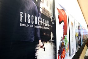 Text auf dem Filmplakat: "Fischertag. Einmal im Jahr kommen sie alle zurück". Das Plakat zeigt einen Menschen von hinten, der im Stadtbach steht und in der Hand eine Pistole hält.
