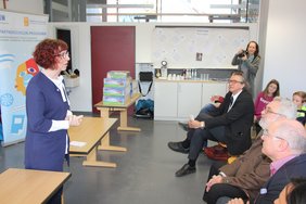 Bürgermeisterin Margareta Böckh steht vor einer Schulklasse. Vor ihr sitzen in der ersten Reihe zahlreiche Erwachsene, dahinter in zwei Reihen die Viertkllässler der Dickenreishauser Grundschule