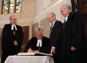 Im Chorraum der Kirche St. Martin trägt sich der neue Landesbischof in das Goldene Buch der Stadt Memmingen ein.